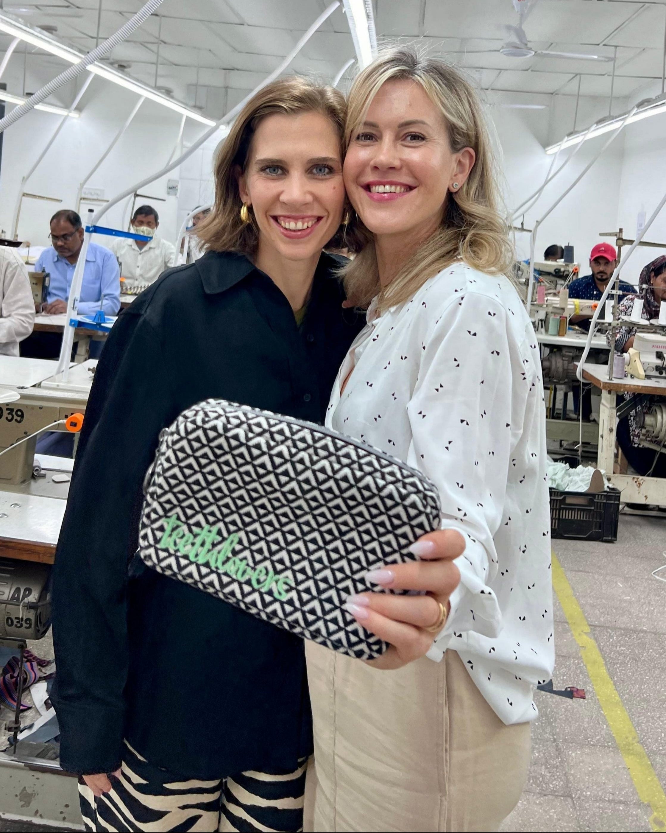 Firmeninhaberinnen Dorina und Wolke in Produktionshalle in Indien präsentieren eine Kosmetik Tasche