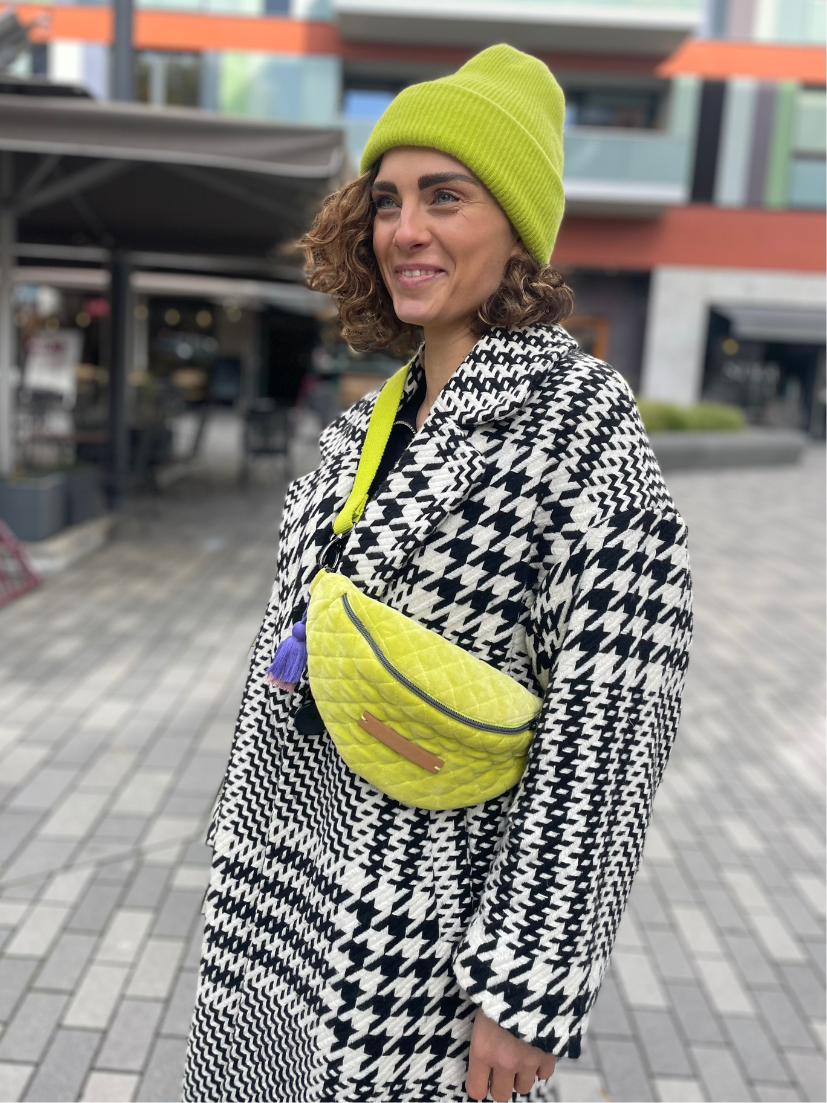 Mini Lime Bumbag mit lila-rosa Tessel in urbanem Kontext.