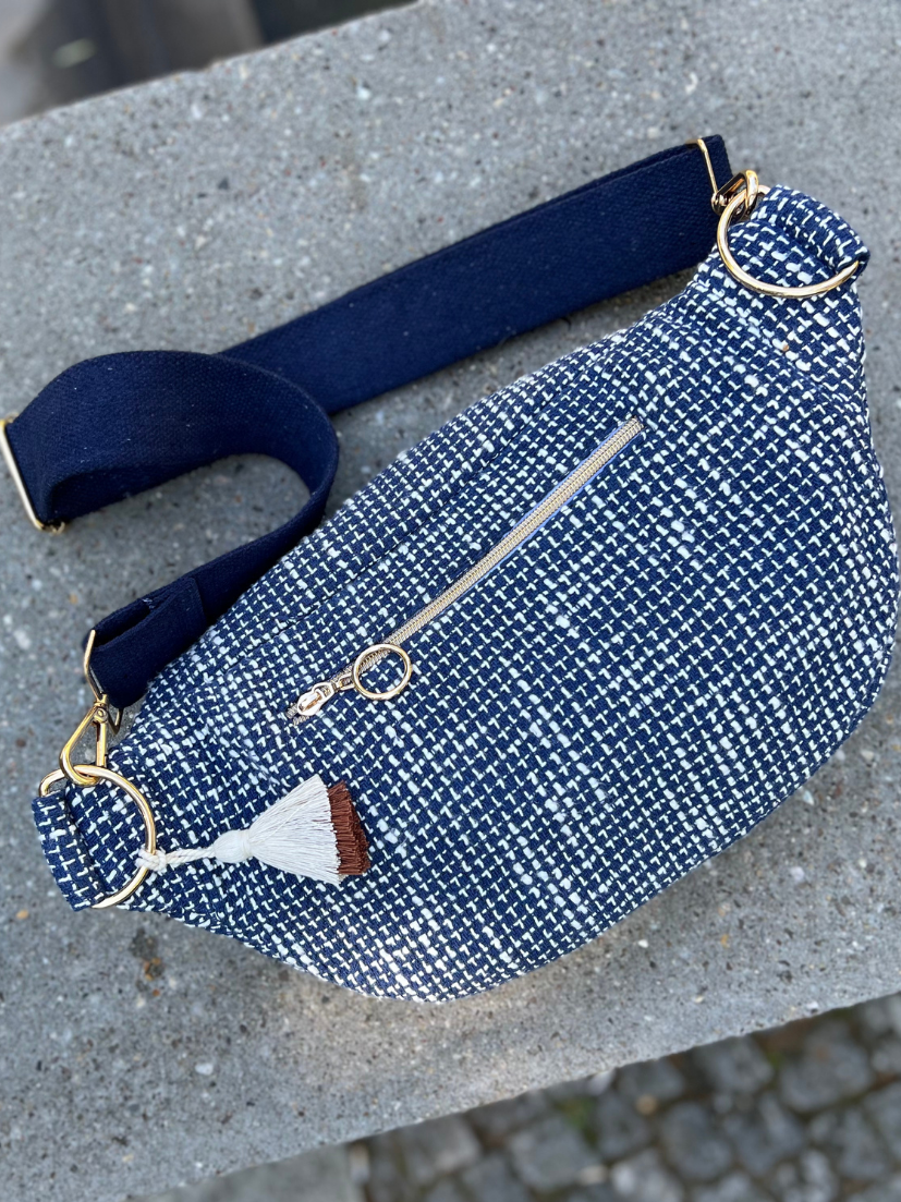 Maxi Bauchtasche in blau-weiß gemustertem Stoff mit goldenen Ösen und breitem Tragegurt von der Rückansicht mit zusätzlichem Reißverschlussfach.