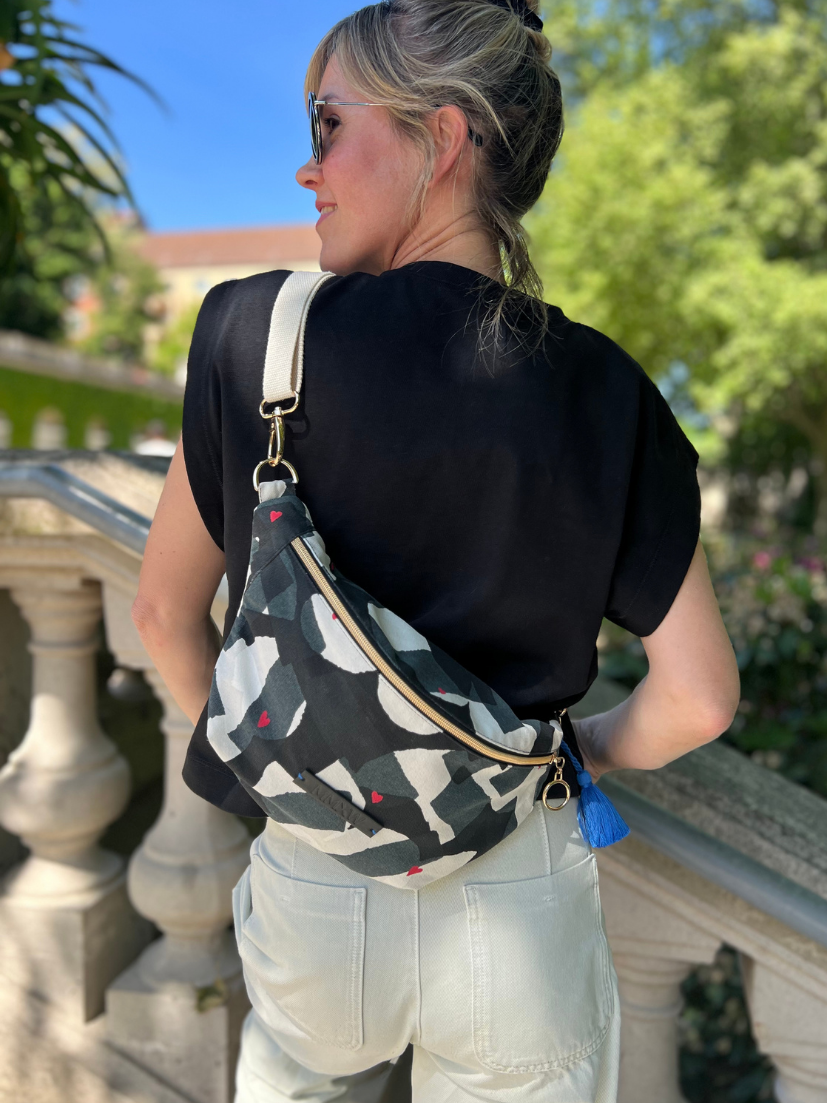 Rückenansicht von Midi-Bumbag mit schwarz/weiß/grauem Print und roten Herzchen Druck.