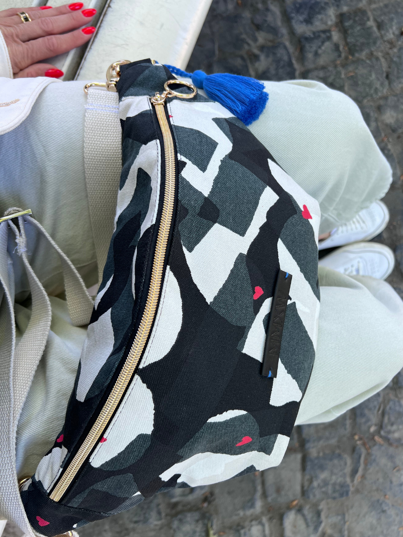 Detailaufnahme Midi Bumbag mit schwarz/weiß/grauem Muster und aufgedruckten Herzchen in Rot.