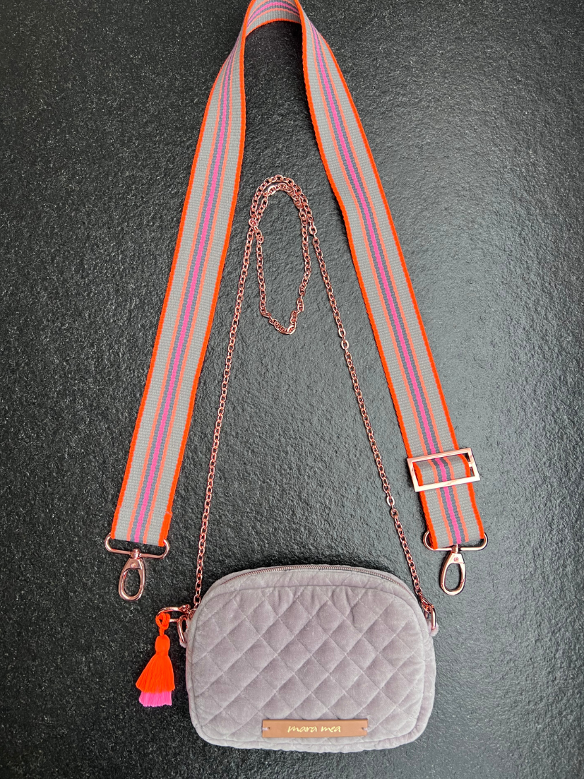 Breiter Extra-Tragegurt in knalligen Neonfarben an grauer Crossbody-Bag aus abgestepptem Samt und passender Quaste in Pink/Orange.