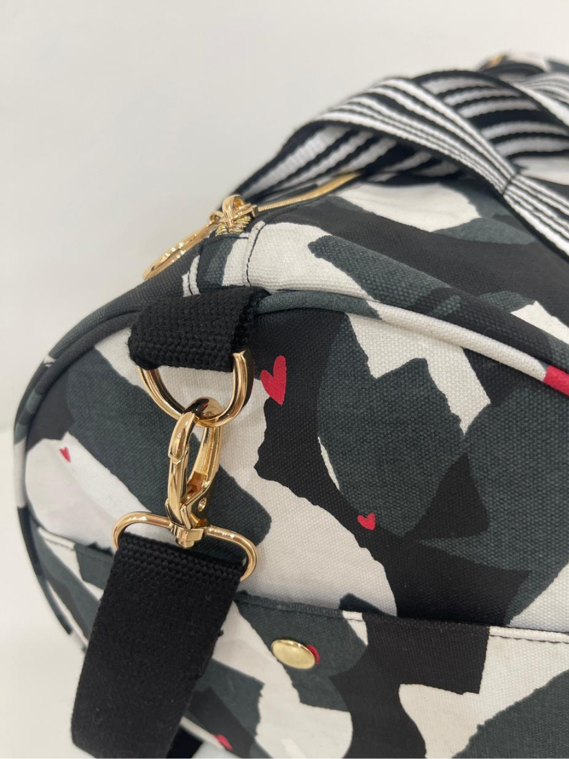 Detailaufnahme der großen Weekender Bag von mara mea. In schwarz-weiß gemustert mit kleinem roten Herzchen Print und goldenen Schnallen.