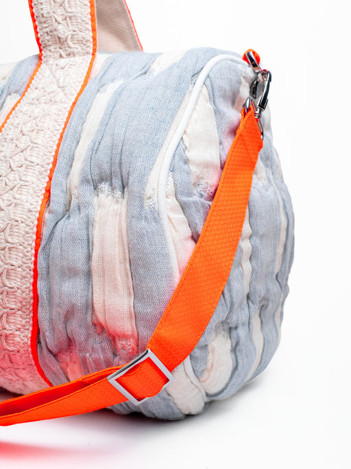 Detailansicht der mara mea Reisetasche breeze babe in Hellblau-Offwhite mit abnehmbarem neon-orangen Schultergurt und silbernen Metallkarabinern