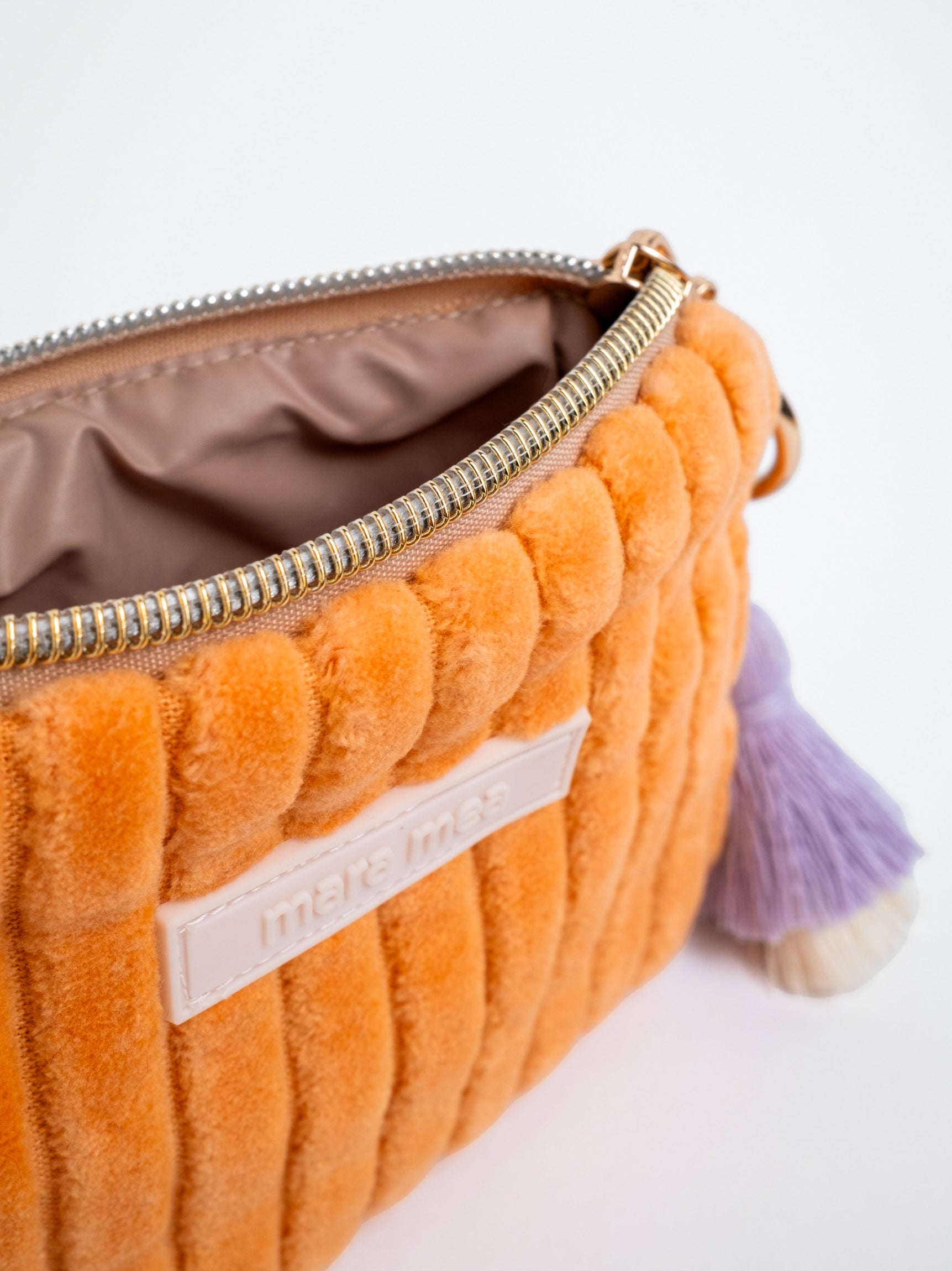 Detailansicht des geöffneten orangefarbenen mara mea Portemonnaies Soft & Spicy Peach aus Cord mit Reißverschluss, Innenfutter, Markenlabel und lilafarbenem Quastenanhänger