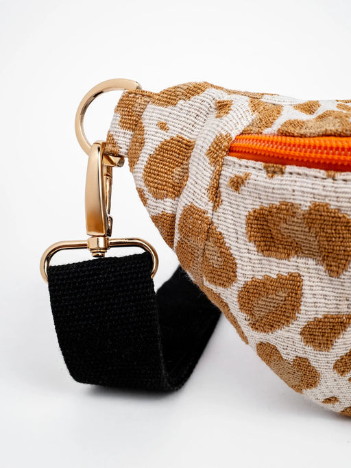 Bauchtaschen Detail Leomuster, goldene Hardware, orangefarbener Karabiner und schwarzer Taschengurt