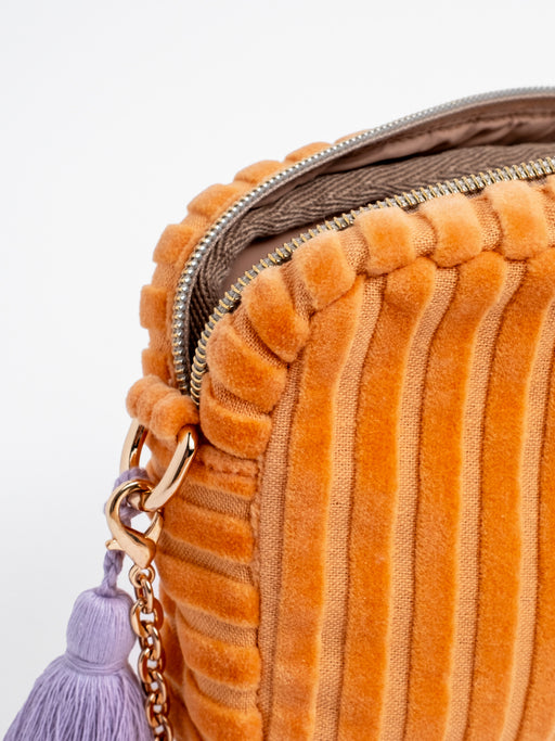 Detailansicht der geöffneten orangefarbenen mara mea Umhängetasche Peach Please Peach aus Cord mit Reißverschluss, Innenfutter und lilafarbenem Quastenanhänger