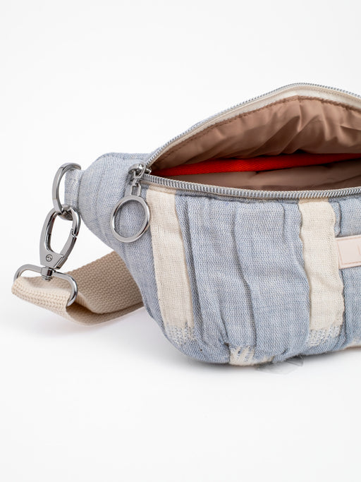 Detailansicht der mara mea Mini Bauchtasche cloud club mit geöffnetem Hauptfach, sichtbaren farbig-abgesetzten Pipings im Innenraum, silbernem Ring-Zipper und abnehmbarem Schultergurt