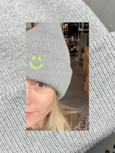 Graue Beanie-Mütze aus 100% recyceltem Polyster mit neongelber Smiley Stickerei vorne drauf.