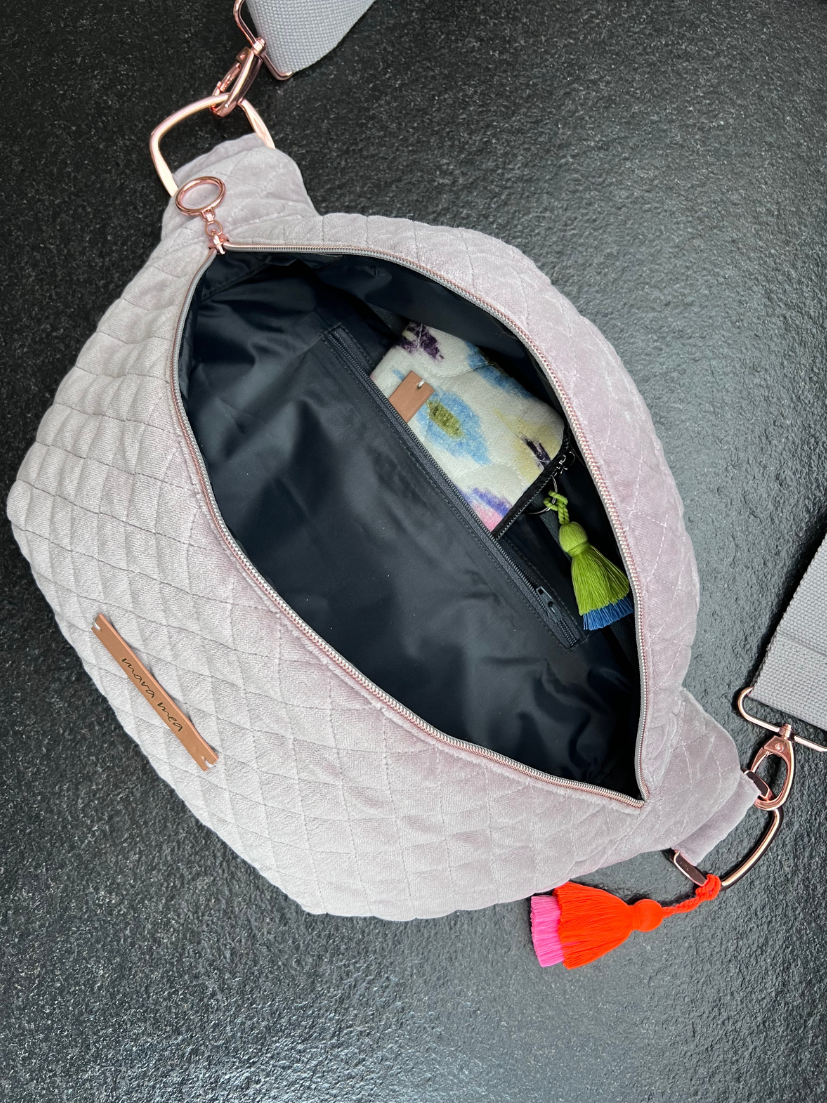 Ansicht von geöffneter Maxi Bumbag in grauen abgestepptem Samt mit knalliger korallenroter/pinker Zierquaste.