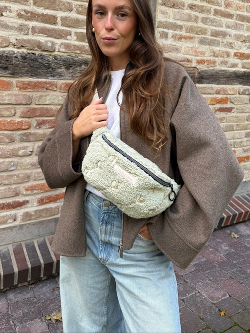 Frau trägt die Mini Bauchtasche soft rebellion crossbody vor dem Körper, Teddystoff in Salbei