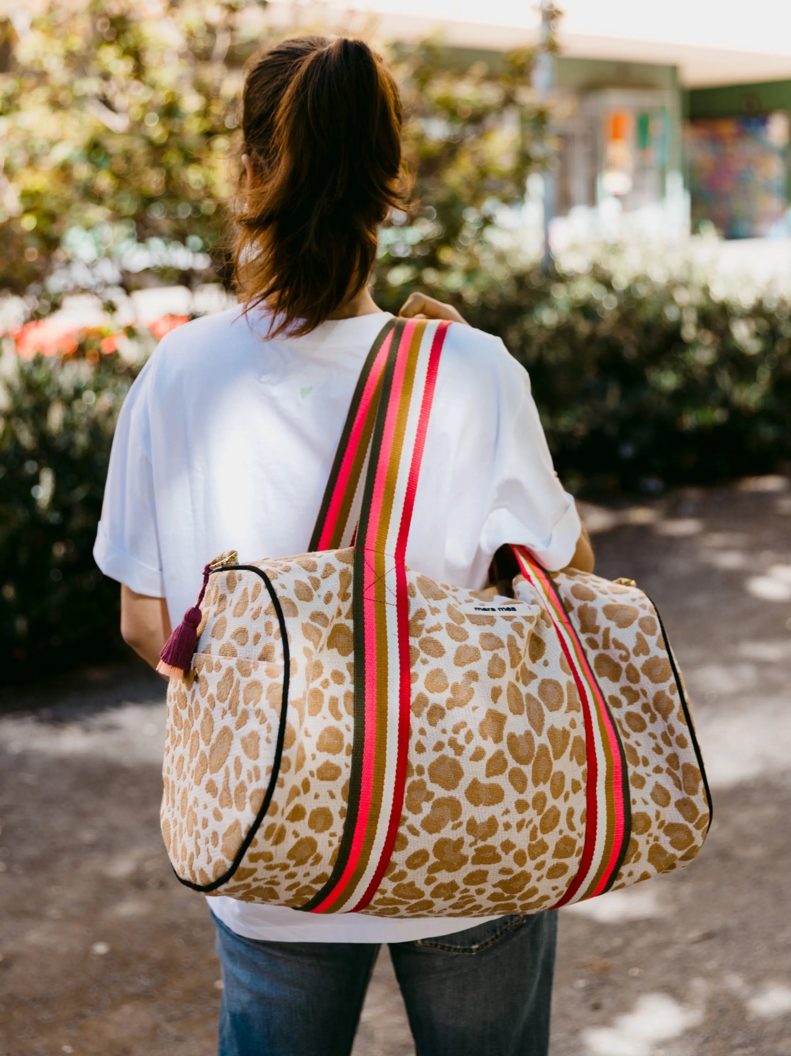 Beige-braune Leo Weekender Reisetasche mit bunt gestreiften Trägern beim City Trip an Frau