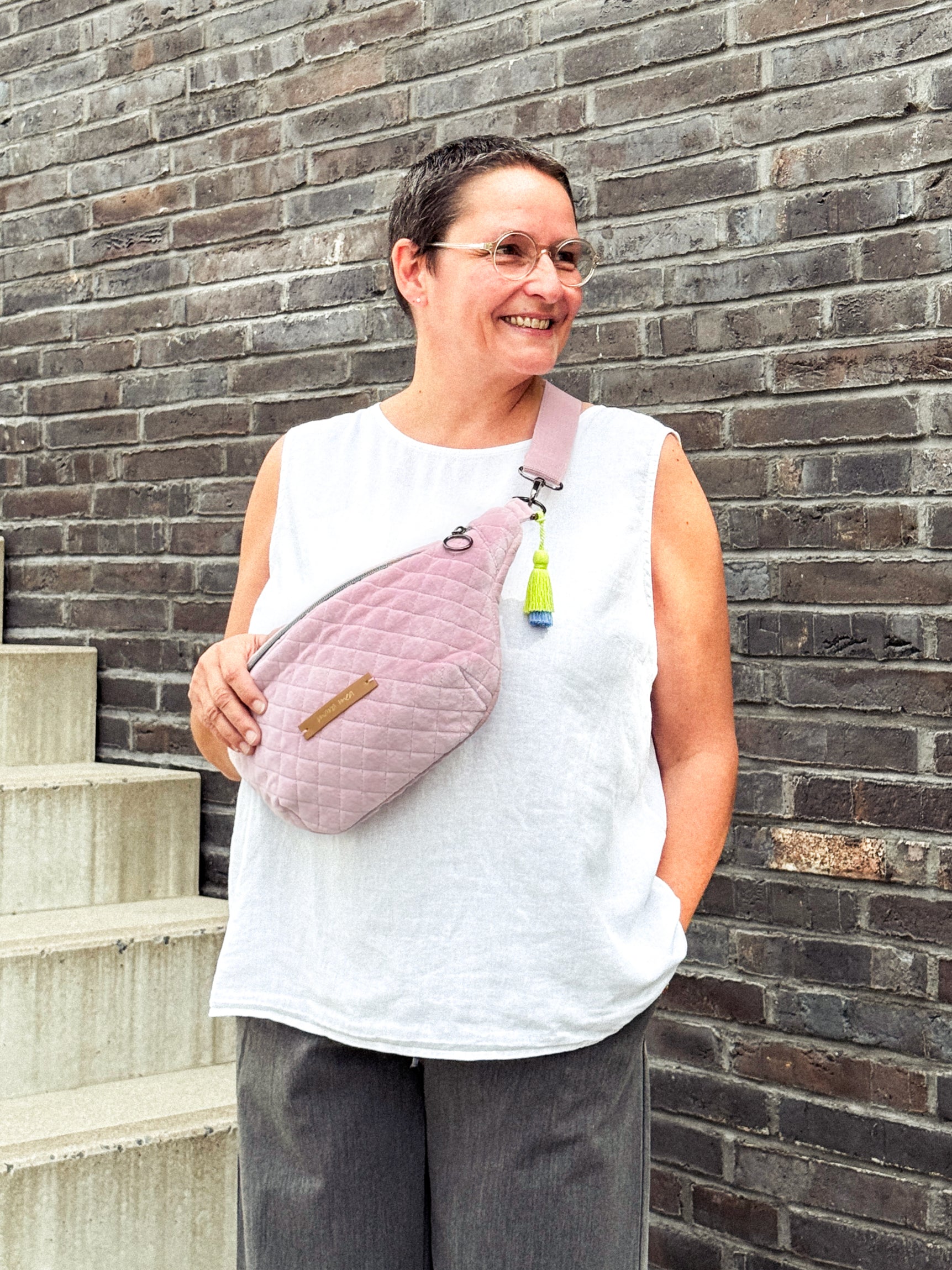 Rosafarbene Bauchtasche aus Samt mit Steppung an Ü40 Model getragen mit kurzen Haaren