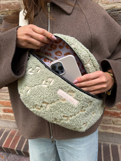 Geöffnete Maxi Bauchtasche snuggle me mit Leo-Innenfutter, Frau steckt ihr Handy hinein