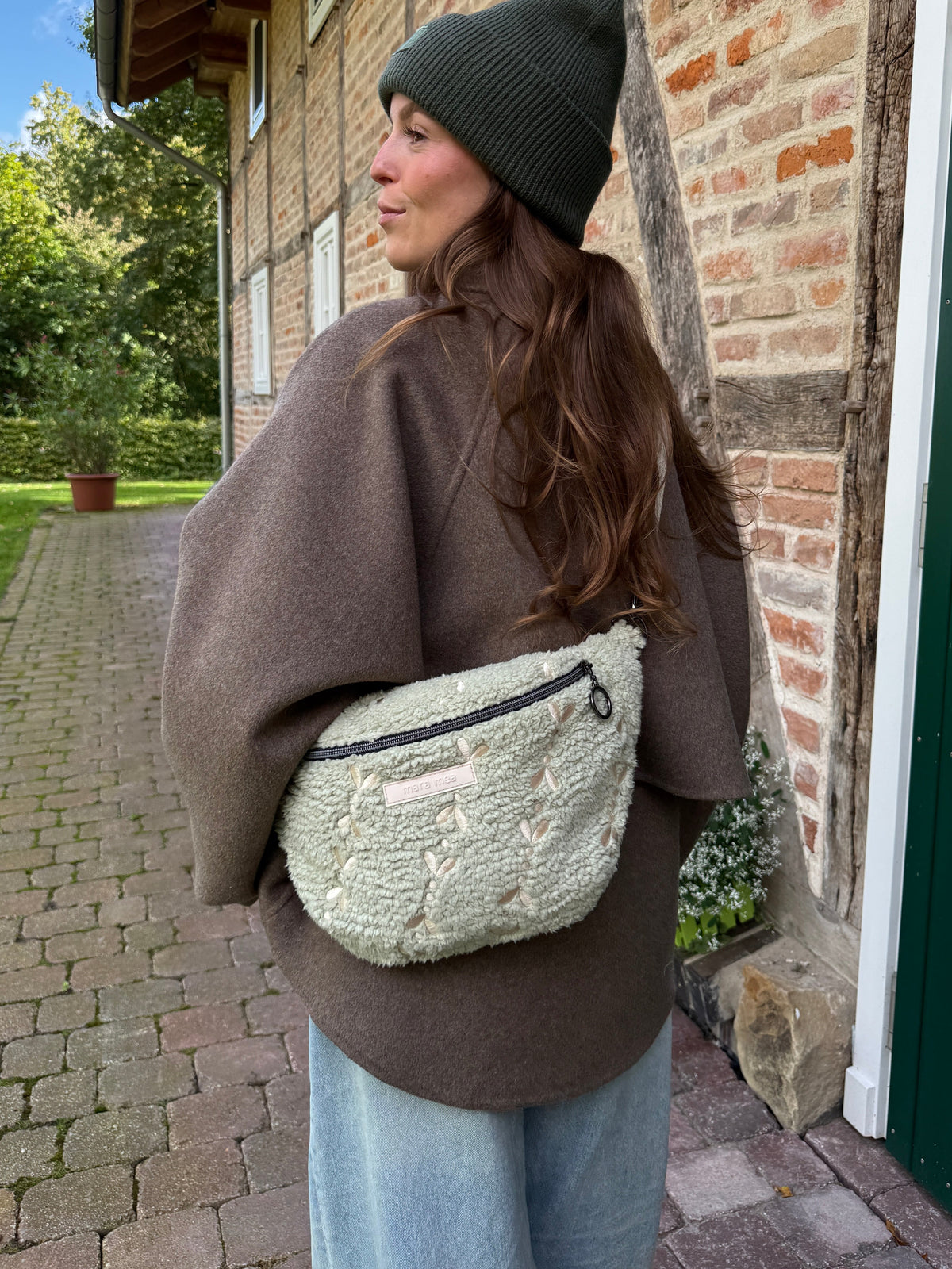 Frau trägt die Midi Bauchtasche cozy chic auf dem Rücken und schaut über die Schulter