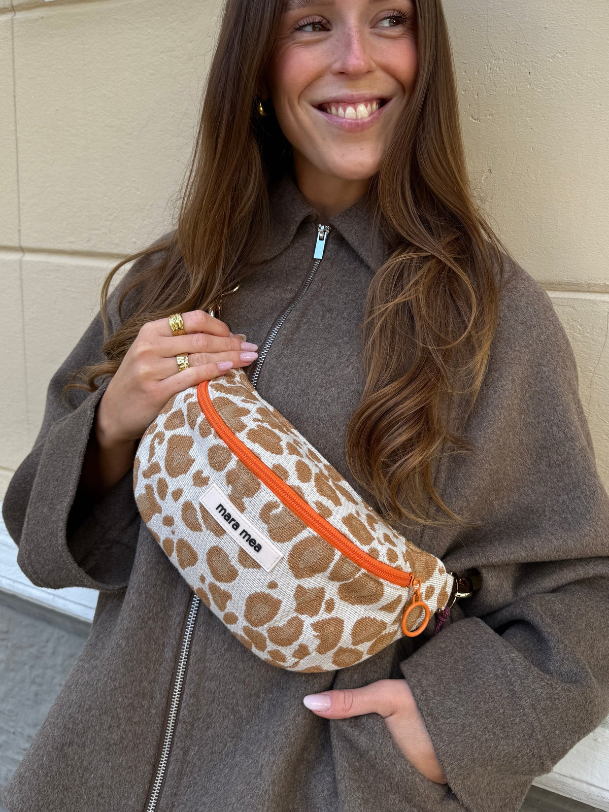 Frau trägt die Mini Bauchtasche heatwave hunter crossbody über einer braunen Wolljacke und lächelt