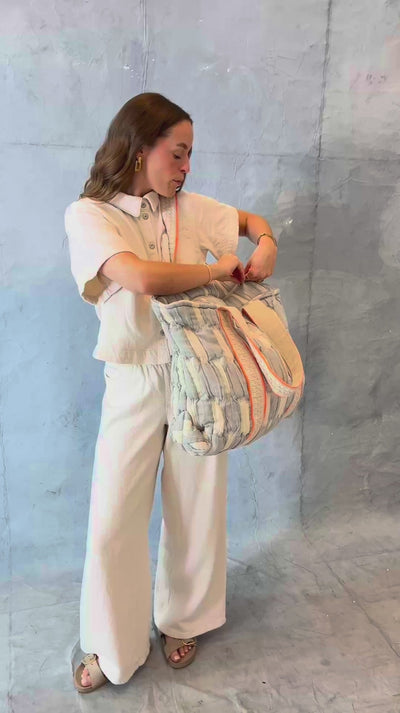 Model öffnet die mara mea Shopper Bag sky state in Hellblau-Offwhite und zeigt Tragegriffe, Reißverschluss und gepolsterten Baumwollstoff