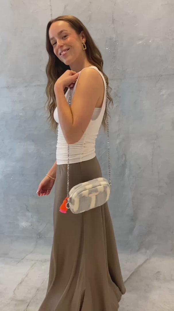 Model trägt die mara mea Umhängetasche air kiss in Hellblau-Offwhite mit silberfarbener Kette und neon-orange-pinker Quaste crossbody im Video, sie zeigt verschiedenen Tragevarianten