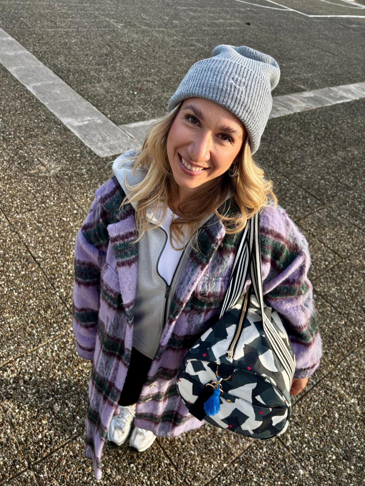 Lächelnde Frau mit der Weekender Bag amore amore über der Schulter, Blick nach oben in die Kamera