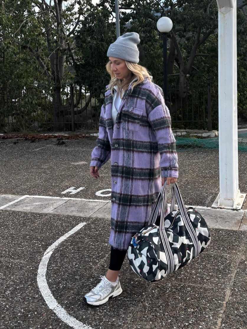 Frau im karierten Mantel trägt die Weekender Bag amore amore an den Henkeln